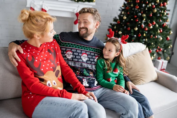 Positive man hugging daughter and wife during christmas celebration at home — Stock Photo