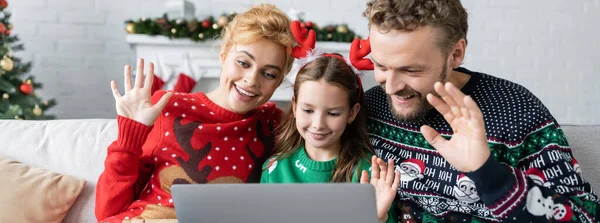 Positive parents with daughter having video call on laptop during christmas at home, banner — Stock Photo