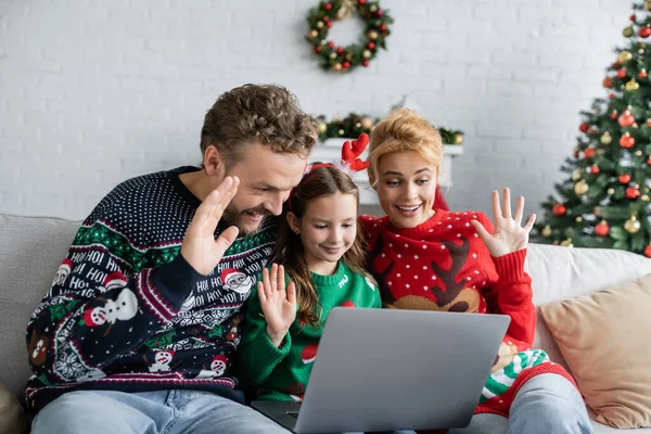 Cheerful family with kid having video call on laptop during new year at home — Stock Photo