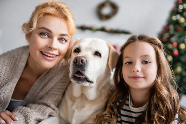 Donna felice sorridente alla macchina fotografica vicino labrador e figlia a casa — Foto stock