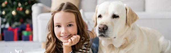 Enfant souriant à la caméra près du labrador à la maison, bannière — Photo de stock