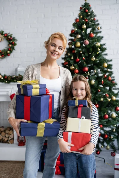 Positive girl holding present near mom during new year celebration at home — Stock Photo