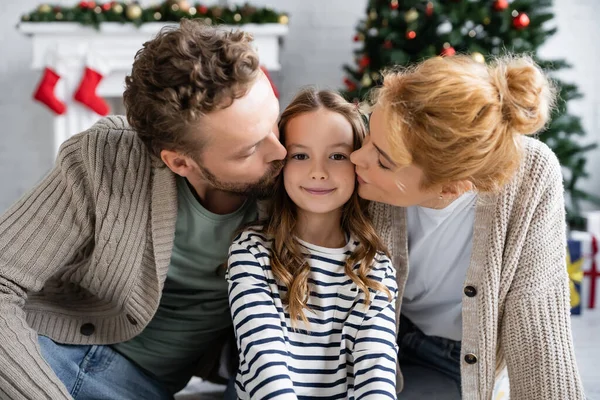 Genitori baciare figlia felice durante il Natale a casa — Foto stock