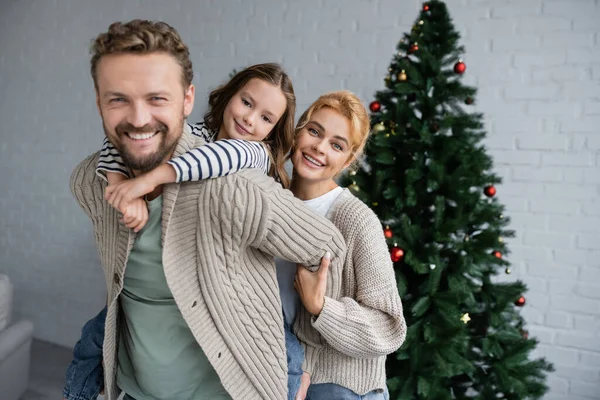 Glückliche Familie beim Umarmen und Blicken in die Kamera während der Weihnachtsfeier zu Hause — Stockfoto