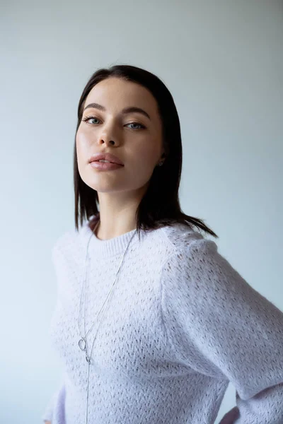 Portrait of brunette woman with natural makeup wearing knitted sweater isolated on grey — Stock Photo