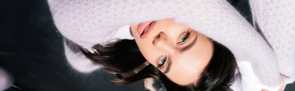 Top view of pretty brunette woman looking at camera while lying on grey background, banner — Stock Photo