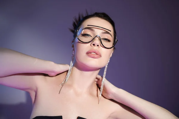 Портрет соблазнительной женщины в модных солнцезащитных очках касающихся шеи на фиолетовом фоне — стоковое фото