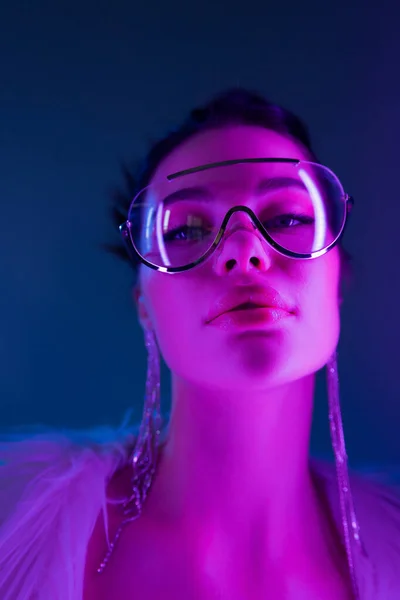 Портрет стильної жінки в сонцезахисних окулярах дивиться на камеру на темно-синьому фоні — стокове фото