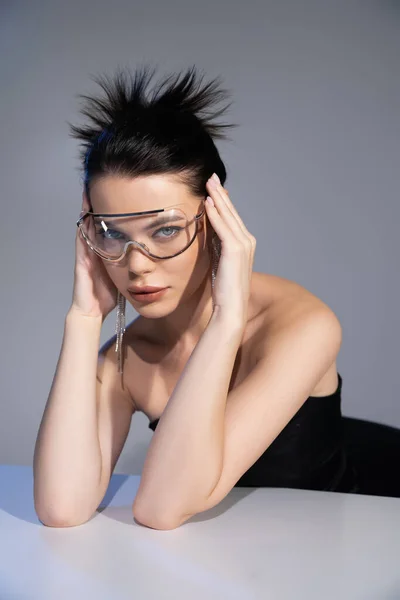 Portrait of stylish brunette woman in sunglasses looking at camera isolated on grey — Stock Photo