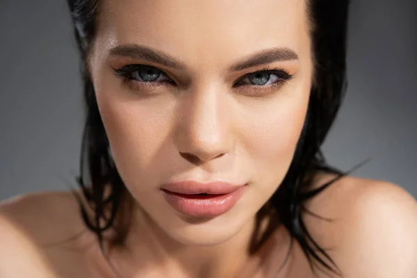 Portrait of brunette woman with makeup looking at camera isolated on grey — Stock Photo