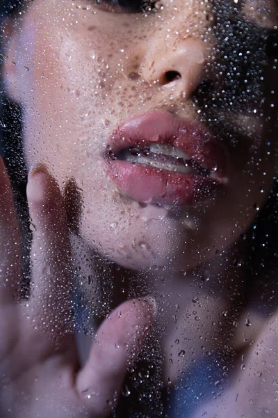 Vue recadrée de femme sexy touchant verre humide sur fond noir — Photo de stock
