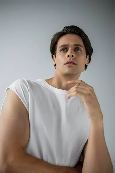 Portrait of dreamy man in white t-shirt looking away isolated on grey — Stock Photo