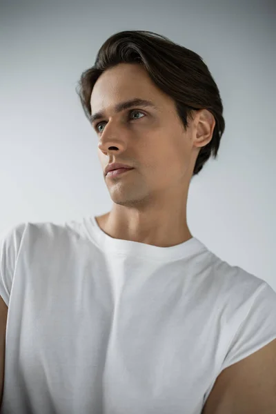 Portrait of brunette man in white t-shirt looking away isolated on grey — Fotografia de Stock