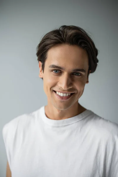 Porträt eines fröhlichen Mannes mit blauen Augen, der in die Kamera blickt, während er isoliert auf grau posiert — Stockfoto