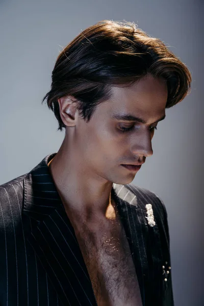 Portrait of brunette man with hairy chest and stylish striped blazer on dark grey — Stock Photo