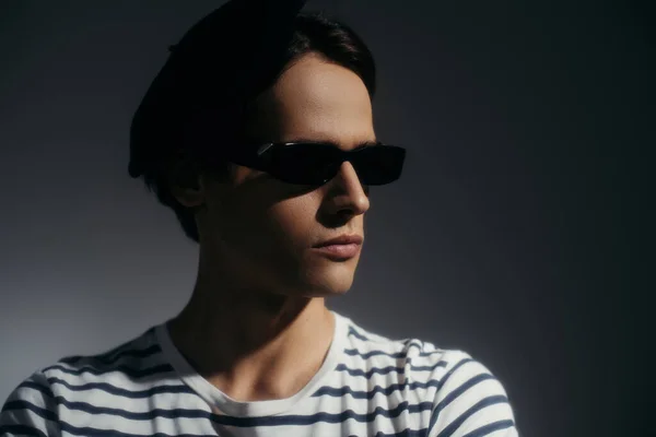 Portrait d'homme élégant en lunettes de soleil posant isolé sur gris avec éclairage — Photo de stock