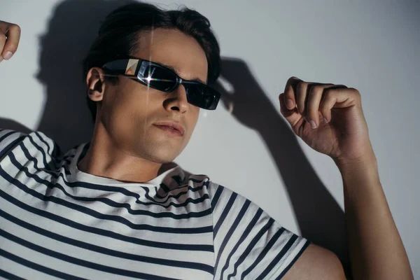 Draufsicht eines Mannes mit Sonnenbrille auf grauem Hintergrund mit Licht und Schatten — Stockfoto