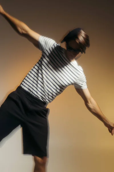 Motion blur of man in striped t-shirt posing on yellow background — Stock Photo