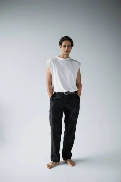 Full length of barefoot man posing on grey background — Stock Photo