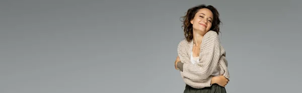 Femme heureuse en cardigan tricoté chaud s'embrassant isolée sur gris, bannière — Photo de stock