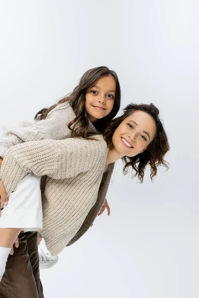 Mère heureuse et fille en tricot chaud regardant la caméra tout en s'amusant isolé sur gris — Photo de stock