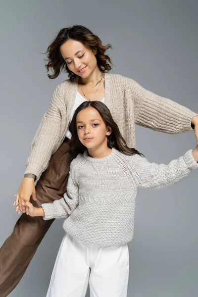 Allegra donna bruna che balla con la figlia guardando la fotocamera isolata sul grigio — Foto stock