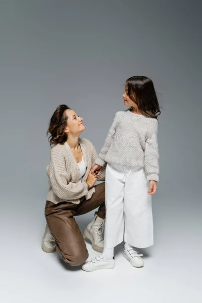 Happy woman holding hand of stylish daughter on grey background — Stock Photo