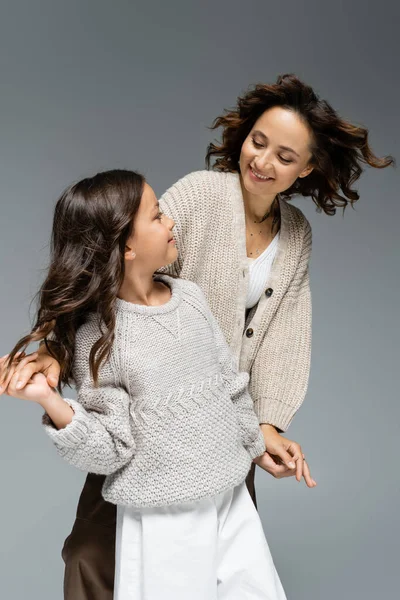 Freudige Mutter und Kind, die einander anschauen und Händchen halten, während sie isoliert auf grau tanzen — Stockfoto
