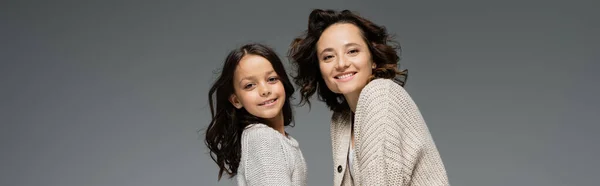 Brunette mother and child in trendy autumn clothes looking at camera isolated on grey, banner — Stock Photo