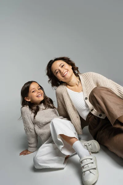 Lächelndes Mädchen mit Mutter posiert in modischer Herbstkleidung auf grauem Hintergrund — Stockfoto