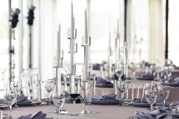 Стильний декор бенкетного столу в ресторані. свічки, окуляри, тарілки на столі . — стокове фото