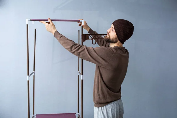 Bearded man assembles a shelf for the rack. — Stock Photo, Image