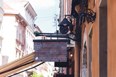 vintage wooden sign suspended on gun on wall of building.