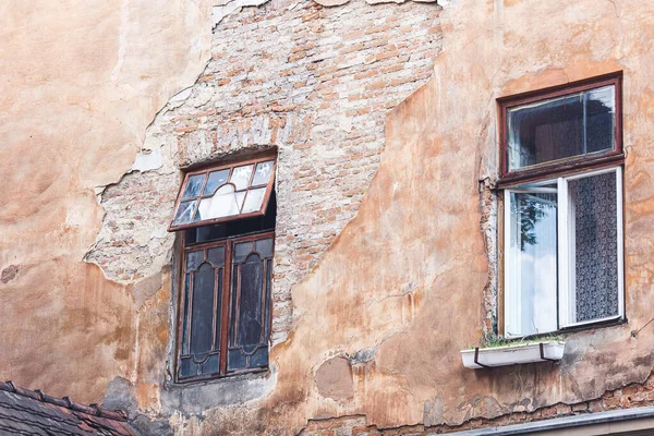 wooden windows on old brick building. Old brick wall with cracked plaster.