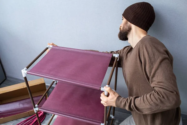 Bearded man assembles a shelf for the rack. — Stock Photo, Image