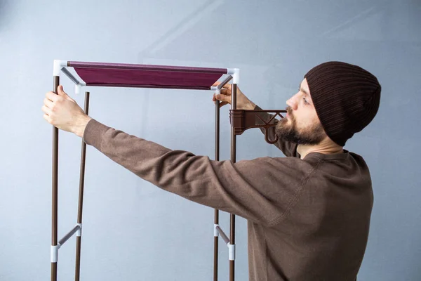 Bearded man assembles a shelf for the rack. — Stock Photo, Image