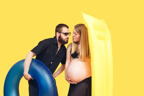 Vousatý Muž Těhotná Žena Drží Nafukovací Prsten Matrace Žlutém Pozadí — Stock fotografie