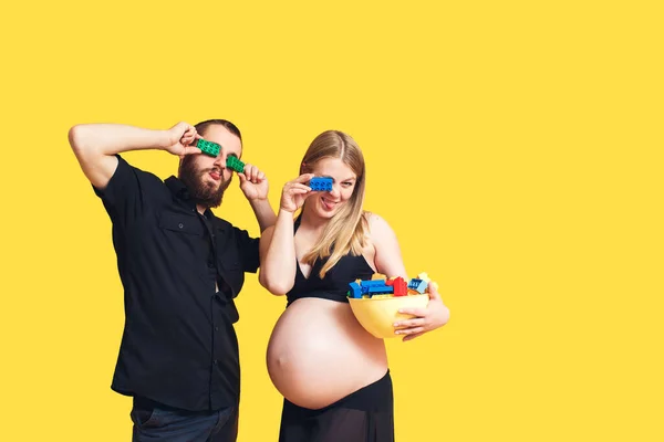 Понятие образа жизни, людей и эмоций. Бородатый мужчина и беременная девушка в купальнике валяют дурака, делая очки с дизайнером на глазах, показывая свой язык — стоковое фото