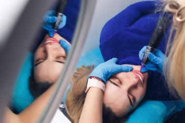 Bir kadın, dövme salonunda kalıcı olarak dudak makyajı yaptırır. Yakın plan..