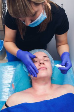 Güzellik salonunda yüz derisine nemlendirici sürmek.