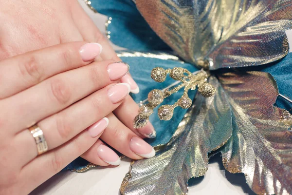 Female hands with a beautiful manicure with glitter on the background of a flower — Foto de Stock