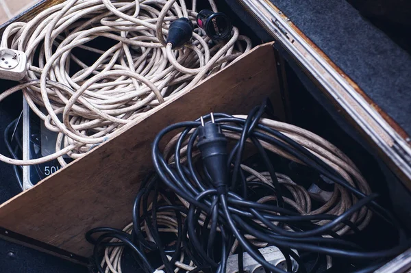 Gamla smutsiga elektriska förlängningssladdar i en låda — Stockfoto