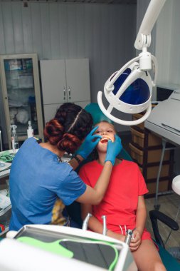 Orthodontist examining dental braces in a teenager girl