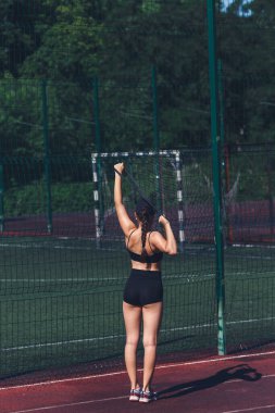 Genç bir kız spor lastiğiyle esneme hareketleri yapar.