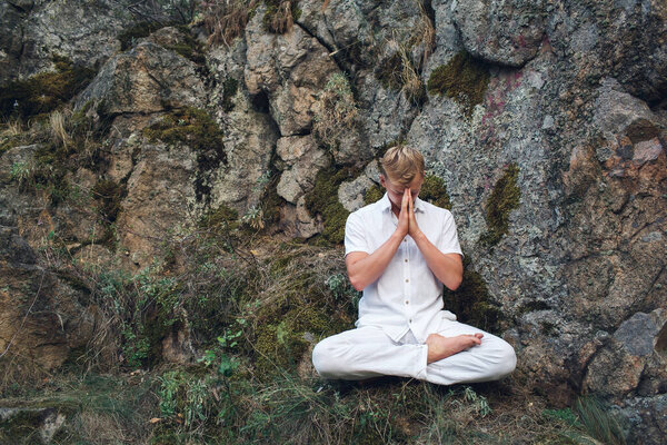 the guy prays in the lotus position sitting on a rock