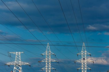 Gökyüzüne karşı yüksek voltajlı bir hattın üç sütunu