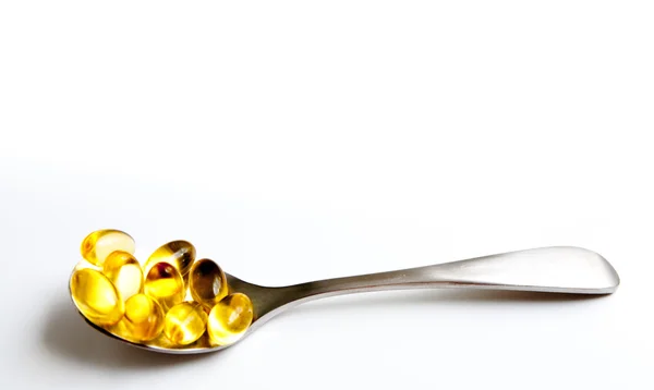 Golden pills on a spoon — Stock Photo, Image