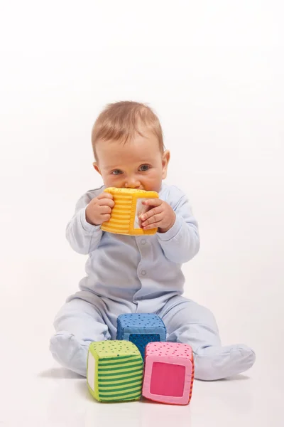 Menino de pijama azul brincando com blocos de cores — Fotografia de Stock