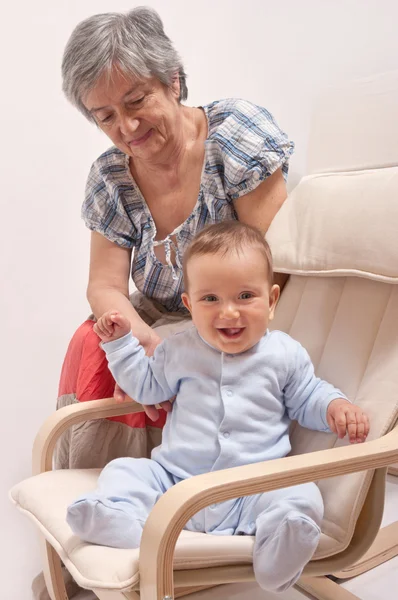 Sandalyede oturan ve büyükannesi ile gülen bebek — Stok fotoğraf