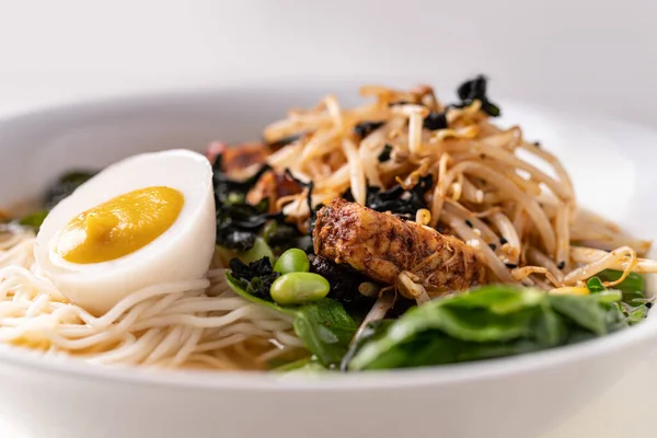 Asian fusion vegan meat-free ramen noodles with mushrooms, fermented tofu, sprout, beans, vegan egg and green pak choi leaves